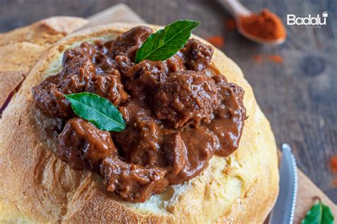 Piatto di gulasch di manzo servito all'interno di una pagnotta svuotata