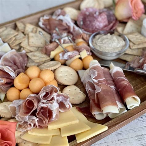 A charcuterie board with prosciutto, melon, cheese, and olives