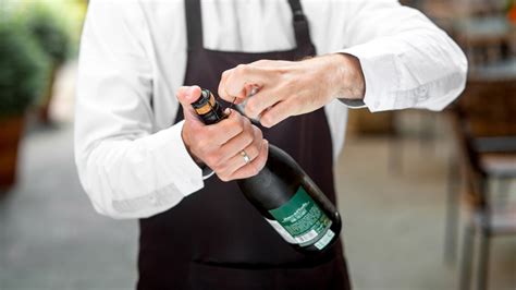 Mano che usa il bordo di un tavolo per aprire una bottiglia di birra