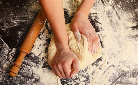 Mani che impastano la pasta fresca su una spianatoia di legno