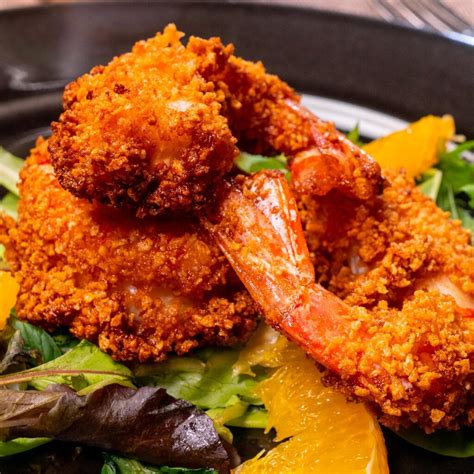 Gamberi fritti che diventano dorati e croccanti nell'olio bollente