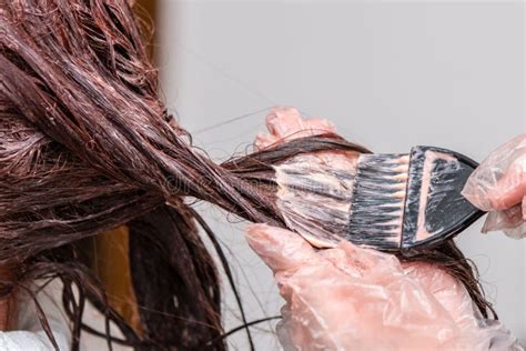 Parrucchiere che applica un trattamento colore ai capelli di una cliente