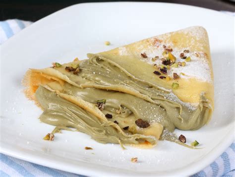 Immagine di un tavolo apparecchiato con crepes al pistacchio e una tazza di caffè