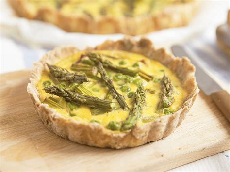 Una tortiera con quiche di asparagi appena sfornata, decorata con punte di asparagi