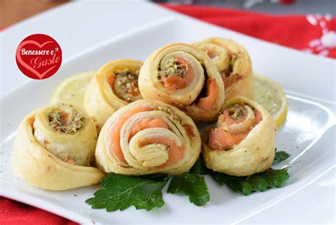 Girelle di pasta sfoglia al salmone disposte su una teglia