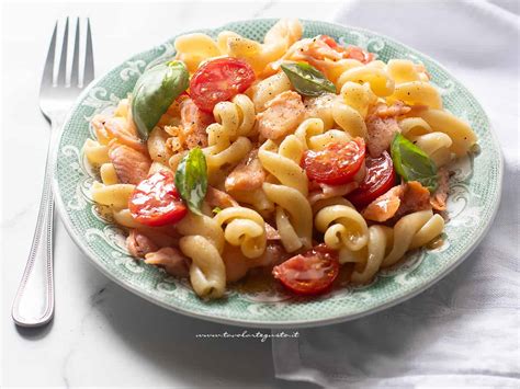 Ingredienti freschi per la pasta con salmone e pomodorini disposti su un piano di lavoro