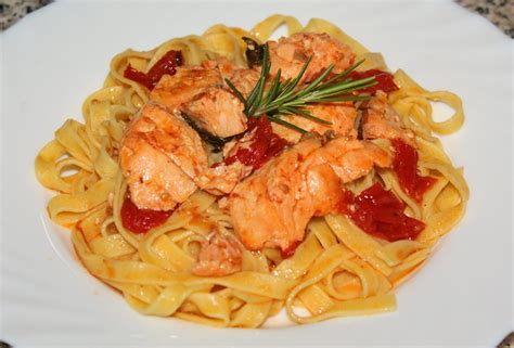 Un piatto di tagliatelle al salmone e pomodorini decorato con basilico fresco