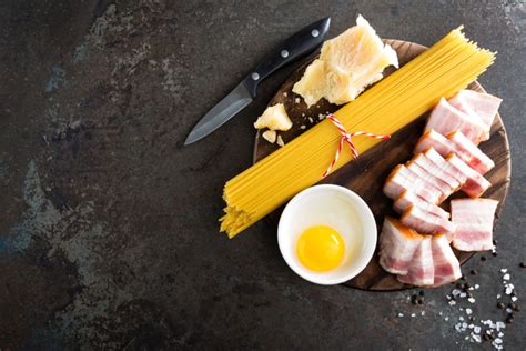 Ingredienti freschi per la carbonara estiva: zucchine, uova, pecorino, prezzemolo, aglio