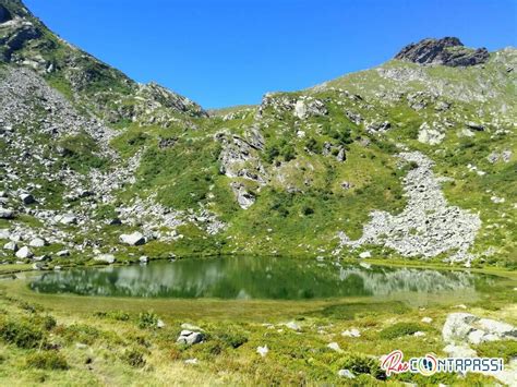 Lago di Pratofiorito circondato da prati verdi in un ampio vallone
