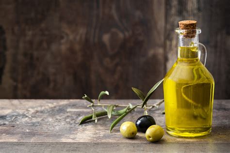 Una bottiglia di olio extra vergine di oliva con olive verdi sullo sfondo