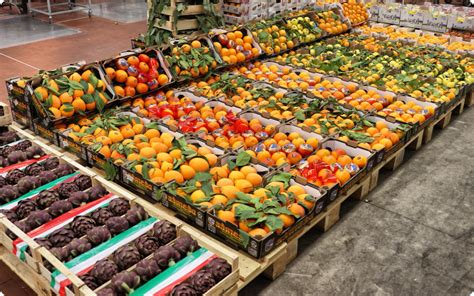 Mercato ortofrutticolo all'ingrosso con bancali pieni di frutta e verdura colorata
