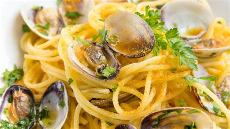 Un piatto di tagliatelle vongole, bottarga e limone servite elegantemente