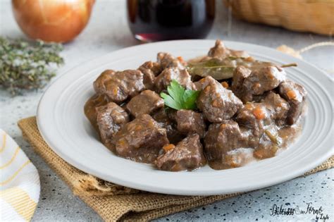 Una tavola apparecchiata con un piatto di spezzatino di manzo e un calice di vino rosso