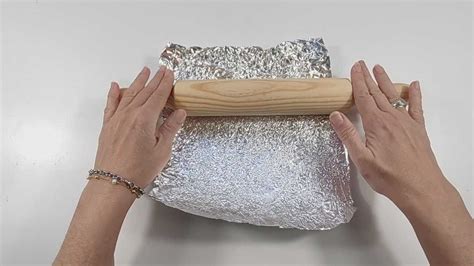 Persona che avvolge carta stagnola per creare un cilindro