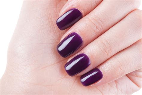 Immagine di mani con unghie color melanzana impeccabili, con focus sulla preparazione delle cuticole