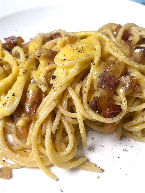 Primo piano di una carbonara cremosa con pancetta croccante