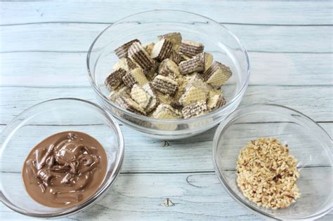 Ingredienti disposti su un piano da cucina: wafer, panna, crema di nocciole, zucchero a velo, granella di nocciole