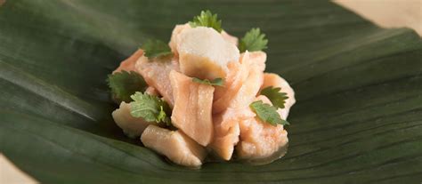 Dettaglio di bocconcini di trota marinata disposti su un piatto con pepe rosa e limone