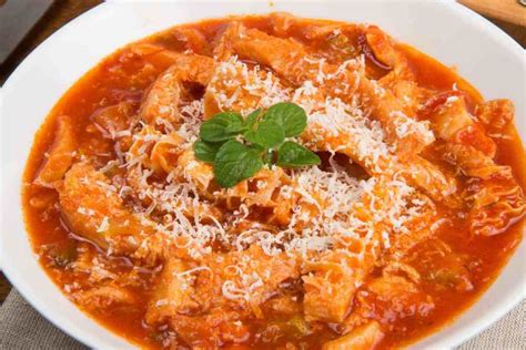 Primo piano di un piatto fumante di trippa alla romana con pecorino e menta