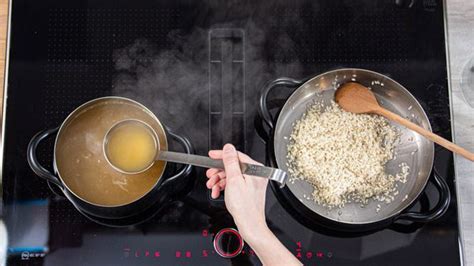 Brodo vegetale che viene versato su un risotto in cottura