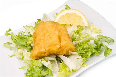 Piatto di baccalà fritto in pastella servito con spicchi di limone