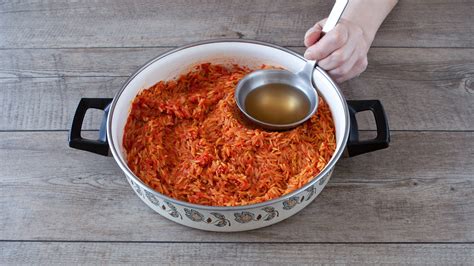 Un mestolo di brodo vegetale caldo viene aggiunto a un risotto in cottura