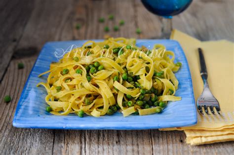 Immagine di un piatto di tagliatelle con piselli, zucchine e pomodorini, guarnito con basilico