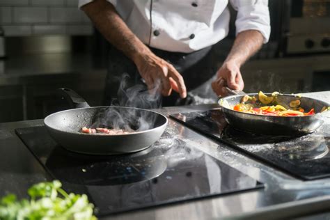 Cuoco che cucina carne e verdure su una piastra Teppanyaki