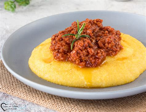 Immagine di una polenta bianca cremosa servita con gamberi succulenti e un sugo rosso brillante.