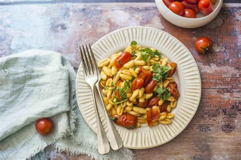 Un piatto di cavatelli alla rucola e olive, guarnito con mandorle e un filo d'olio.