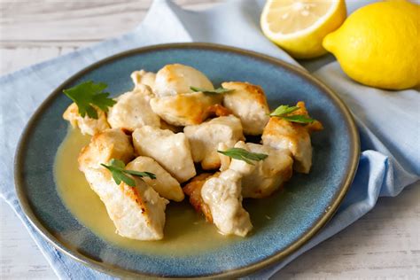 bocconcini di pollo al limone serviti in un piatto con prezzemolo tritato