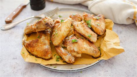 Piatto di alette di pollo piccanti servite con un contorno di patate arrosto e insalata fresca