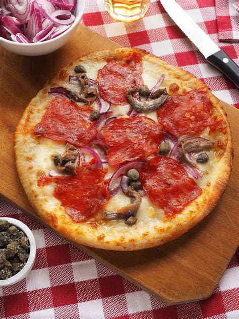 Pizza con salame e cipolla pronta per essere infornata