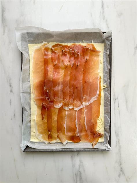 Rondelle di porro e fette di speck su una teglia