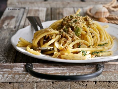 Ingredienti per la pasta con alici fresche disposti su un tavolo di legno