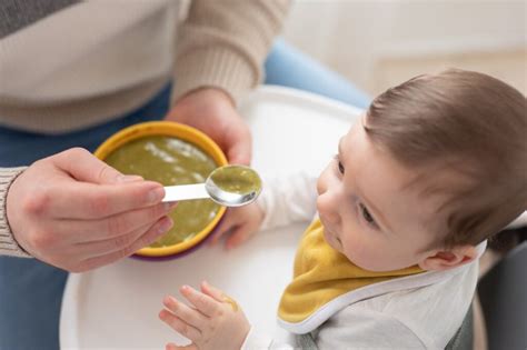 Bambino che mangia la pappa con un cucchiaino