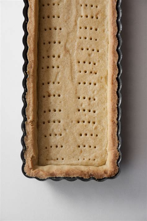 pasta frolla stesa nello stampo con carta forno e legumi secchi