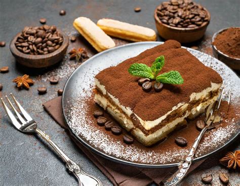 Immagine di ingredienti per il tiramisù disposti su un piano di lavoro: uova, mascarpone, caffè, savoiardi, liquore.