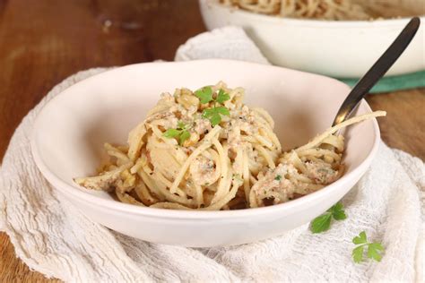 Un piatto di spaghetti conditi con salsa di noci e guarniti con maggiorana