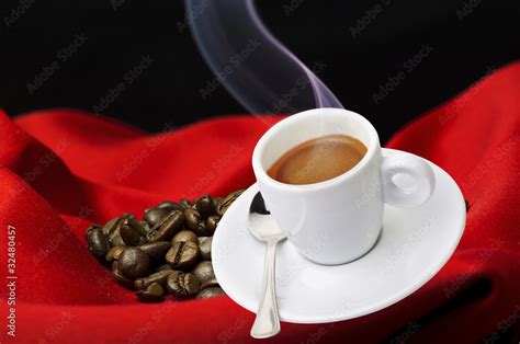 Immagine di una tazzina di caffè fumante accanto a un cornetto