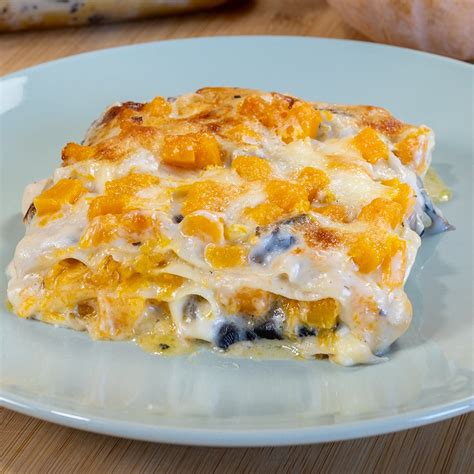 Un primo piano di una porzione di lasagna zucca e ricotta con speck