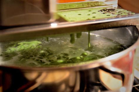 Grattugia per spätzle posizionata sopra una pentola di acqua bollente