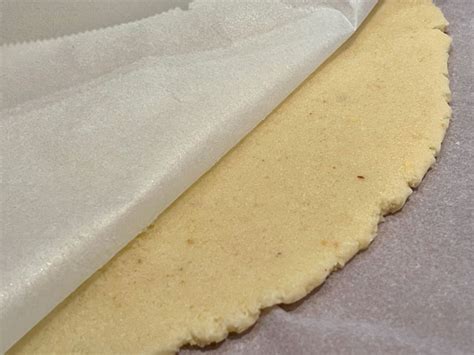 Immagine di pasta frolla stesa tra due fogli di carta forno