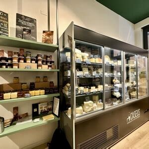 Interno di una bottega di formaggi con un lungo bancone e diverse varietà di formaggi esposti