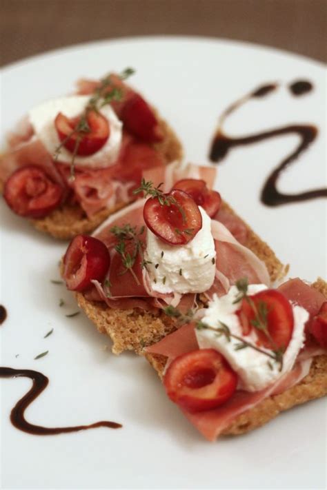 Un piatto con crostini di pane, formaggio caprino e ciliegie