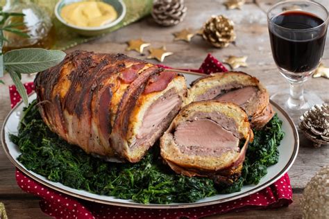 Un tavolo apparecchiato con un grande arrosto al centro, circondato da contorni