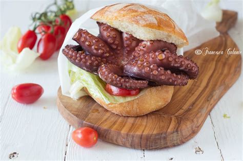 Primo piano di un panino con polpo arrosto, insalata e pomodorini