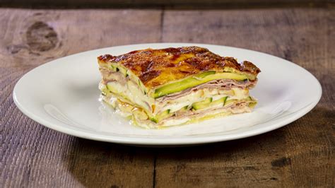 un primo piano di una parmigiana di zucchine e pesce in fase di composizione