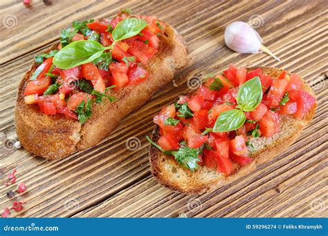 Immagine di una bruschetta guarnita con acciughe del Cantabrico, pomodoro e basilico